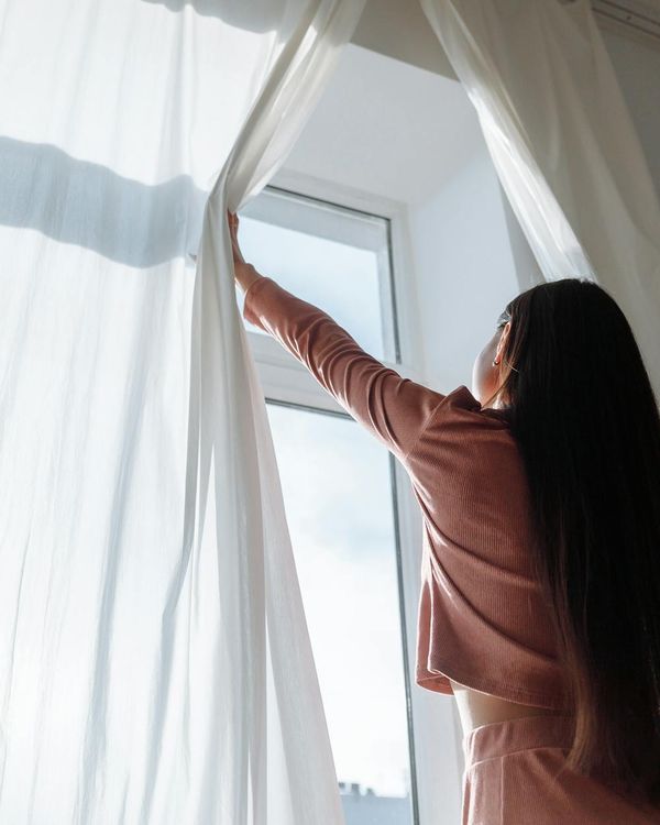 Woman performing a gentle yoga stretch in a bright, airy room.
